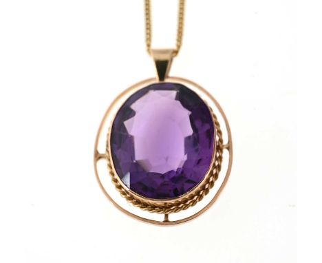 An early 20th century 9ct gold amethyst pendant, within a rope-twist border and polished halo surround, suspended from a late