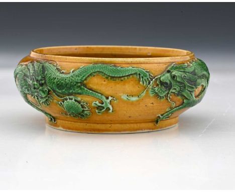 A Chinese porcelain relief moulded water pot, Tang style colours of yellow and green, modelled with two dragons to the exteri