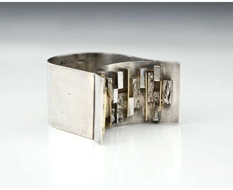 A Modernist silver and parcel gilt napkin ring, LC-F, London 1966, double arched band form with textured block and shard deco