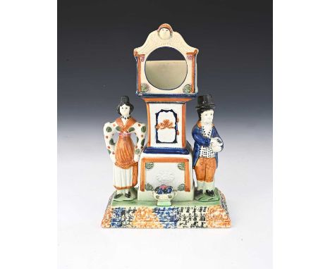 A Staffordshire Prattware watch holder, circa 1830, modelled as a longcase clock flanked by figures of a man and woman, relie