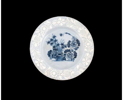 A Bristol Delft bianco sopra bianco plate, circa 1750, painted with a floral still life with fence in the Chinese style, with