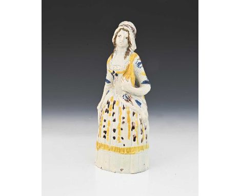 A Prattware figure of a woman holding a bottle of gin, circa 1800, hollow moulded construction, stipple decorated, 21cm high