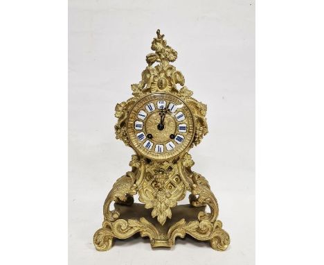 French mantel clock in a gilt metal rococo style body, Roman enamel numerals to the dial, the glazed rear door revealing bell