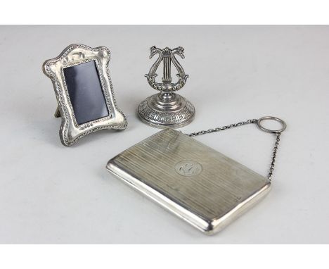 A George V silver lady's card and writing case (marks worn), a George V silver photograph frame (for photos 3cm x 5cm) and a 