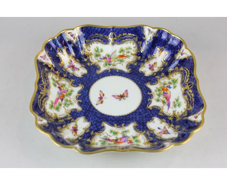 A Royal Worcester scalloped edged square dish decorated with hand painted panels of birds and butterflies on blue ground with