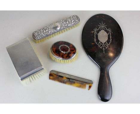 A Victorian tortoiseshell and silver inlaid hand mirror, a Victorian silver mounted tortoiseshell clothes brush in case with 