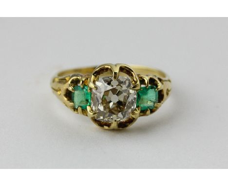 An emerald and diamond three stone ring, the old cushion cut stone claw set with a square cut emerald each side