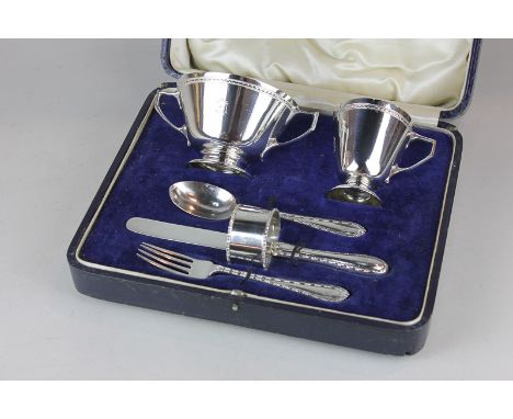 A George V cased silver christening set comprising two-handled bowl, christening mug, knife, fork, spoon and napkin ring, mak