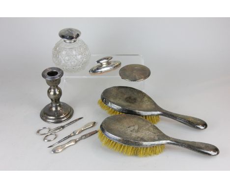 A pair of George V silver backed hair brushes, a silver compact, a silver mounted glass dressing table bottle, a silver mount