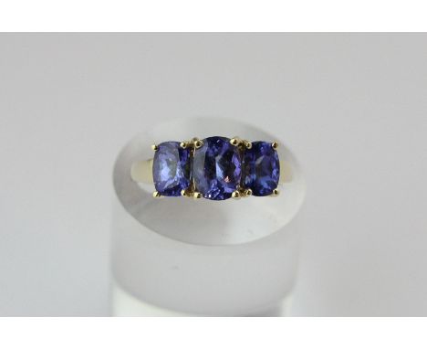 A Tanzanite three stone ring, four claw set with graduated cushion cut stones in 14ct gold