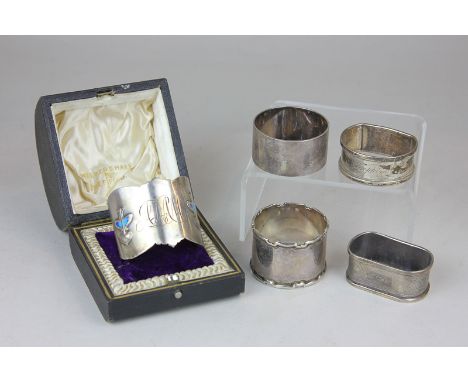 An Art Nouveau cased silver and enamel napkin ring monogrammed, marks worn, together with four various silver napkin rings, 4