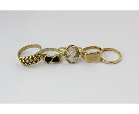 A 9ct gold and black onyx ring; a shell cameo ring; three gold rings