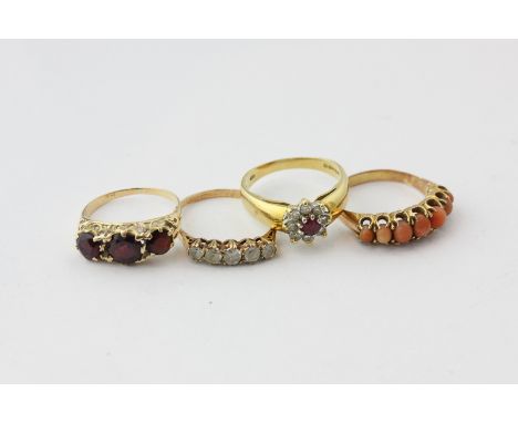 A ruby and diamond cluster ring; a garnet three stone ring; a coral ring and a white sapphire ring