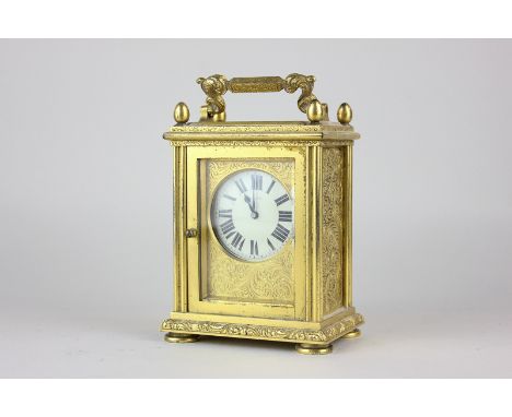 An ormolu and bevelled glass cased carriage clock with Tiffany movement, scroll decoration and egg shaped finials, on pad fee