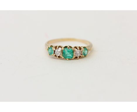 An emerald and diamond five stone ring claw set with round and step cut graduated stones