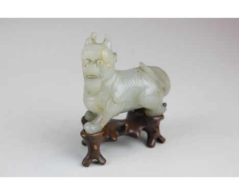 A Chinese carved mutton fat jade temple dog on hardwood stand, 7cm wide