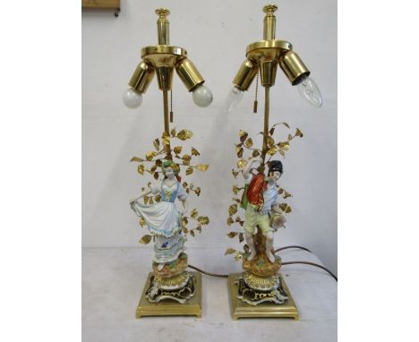 A pair of Sergio Mangani ceramic table lamps of a man and woman with gold plated leaf details on a brass stand, with shades c