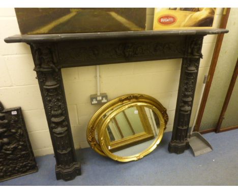A Victorian style cast iron fire surround; cast with putti, bird and scroll decoration; the internal measurements 46" x 56"