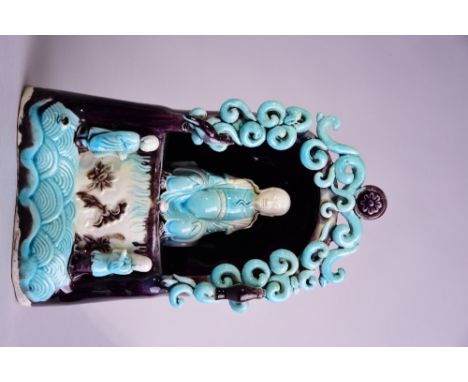 Chinese turquoise and aubergine-glazed figure of Zhenwu, modelled within a grotto, beneath an arch of openwork scrolling clou