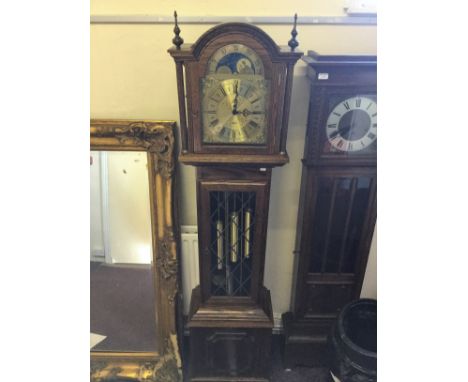 A reproduction oak grandfather clock of Fenclocks, Suffolk, with carved wooden base and glass case with diamond pattern frami