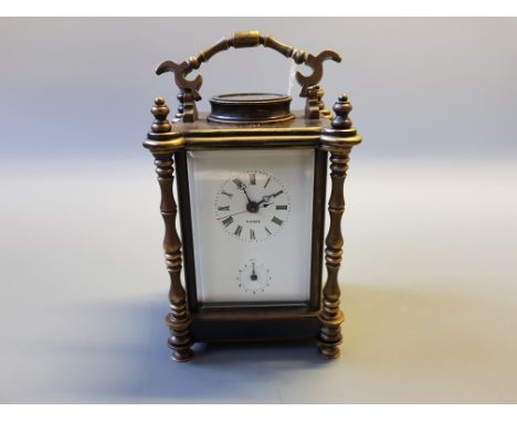 A brass cased carriage clock with bevel glass panels, turned column supports, white enamel dial by Mudger.