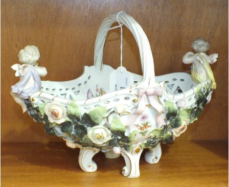 A late-19th/early-20th century German ceramic basket with handle and applied cherubs, floral and ribbon decoration, 20cm high
