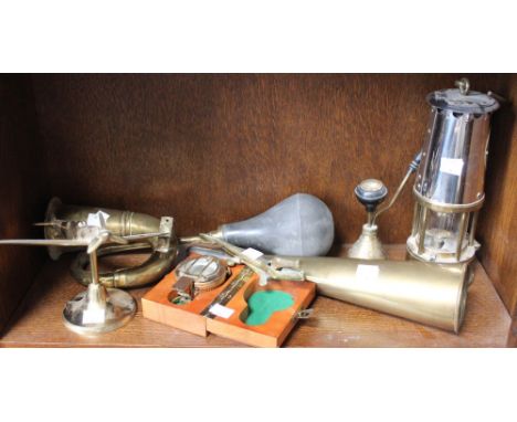 A shelf containing a selection of brass items including, Spitfire, Miners Lamp, Car Horn, Compass, etc