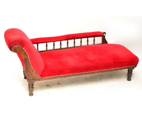 A late Victorian burgundy upholstered chaise longue raised on ring turned legs.