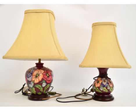 Two Moorcroft lamp bases in the "Pansy" pattern on dark pink ground, one of shouldered baluster form and the other of squat b