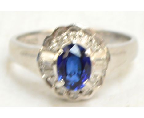 A platinum diamond and sapphire dress ring, the central raised oval sapphire surrounded by ten small round and six small squa