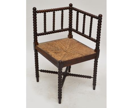 A c.1900 oak bobbin turned corner chair with rush seat.