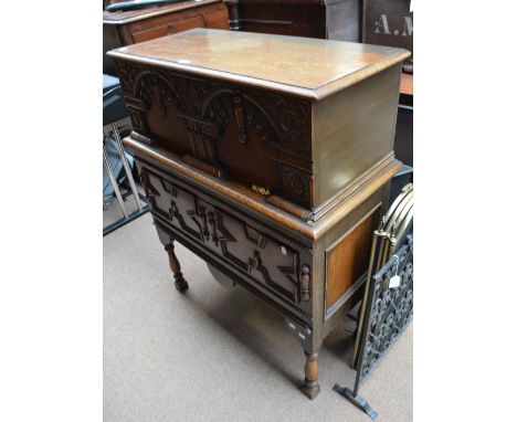 An early to mid 20th century oak side cabinet, the upper section with hinged lid above moulded front, geometrically moulded d