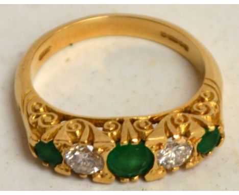 An 18ct yellow gold five stone ring with scroll decorated setting with two diamonds alternating with three green stones, Lond