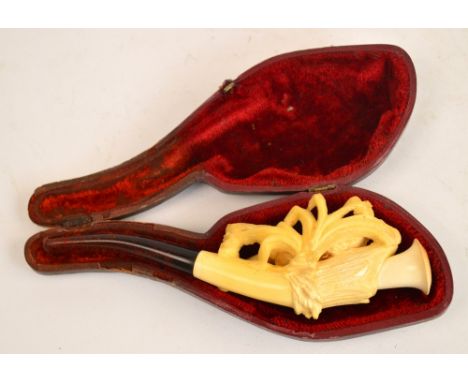 A cased Meerschaum pipe carved as a bird perched on a branch amongst leaves.