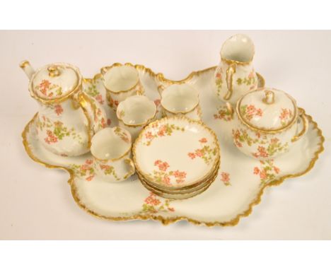 A c.1900 French Limoges floral decorated gilt heightened coffee set comprising shaped tray, coffee pot, sucrier, jug, four cu