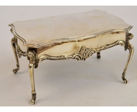 An Edwardian hallmarked silver trinket box modelled as a French desk, the serpentine outlined hinged lid revealing a velvet l