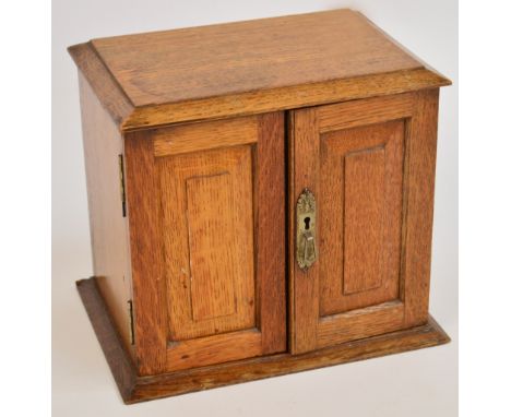 An Edwardian oak letter/writing cabinet, with doors and hinged top enclosing a letter rack, a pen rest and clear glass inkwel