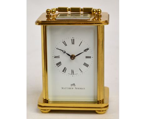 A cased contemporary brass cased carriage clock by Matthew Norman, bearing presentation plaque dated 1993, with swing loop ha