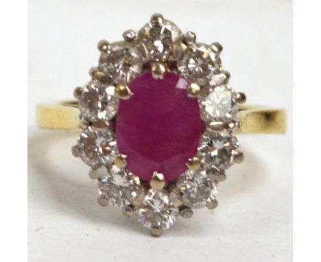 An 18ct yellow gold diamond and ruby ring, the oval cut ruby surrounded by ten brilliant cut diamonds, size M.