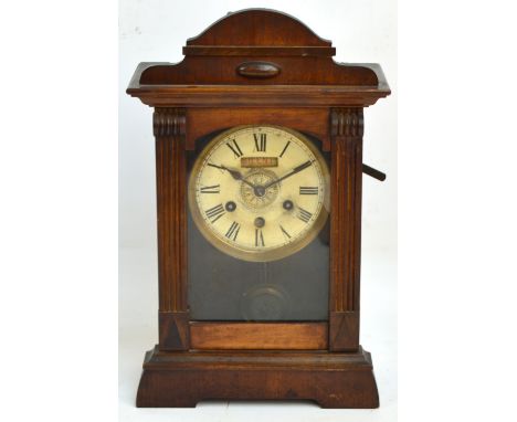 An early 20th century American walnut cased eight day alarm mantel clock with circular dial set with Roman numerals and silen
