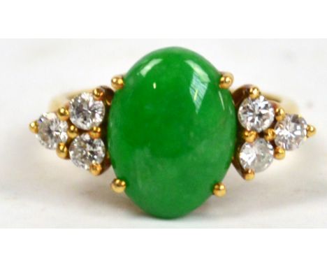 An 18ct yellow gold ring set with oval green jadeite stone flanked by six brilliant cut diamonds, size H/G.