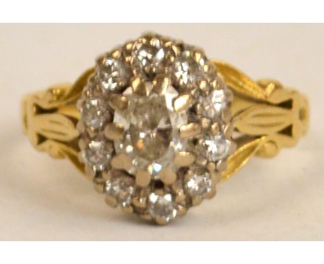 A yellow metal diamond cluster ring, the central stone approx 0.6cts, with foliate decorated arms, size N, 5.7g. CONDITION RE