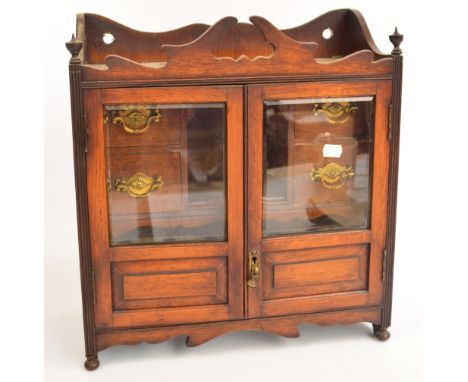 An Edwardian oak smoker's cabinet with glazed doors enclosing drawers, central aperture and pipe rack, sold with a quantity o