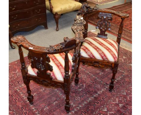 A reproduction carved mahogany conversation sofa, decorated with masks and scrolling leaves