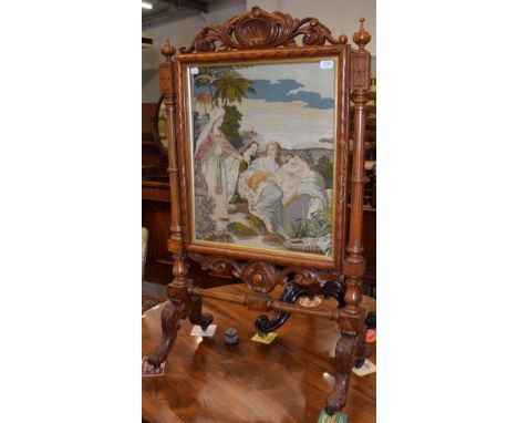 A Victorian carved walnut firescreen, inset with a needlework panel, 121cm high by 71cm wide 