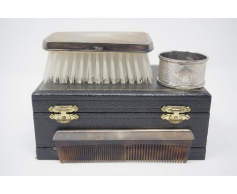 An unused cased silver backed gentleman's brush and comb set, maker Broadway and Co. and a silver napkin ring, both with engi
