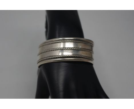 A Mexican silver bangle, a silver bangle stamped 925 and a silver studio made brooch, total weight approximately 105.6 grams.