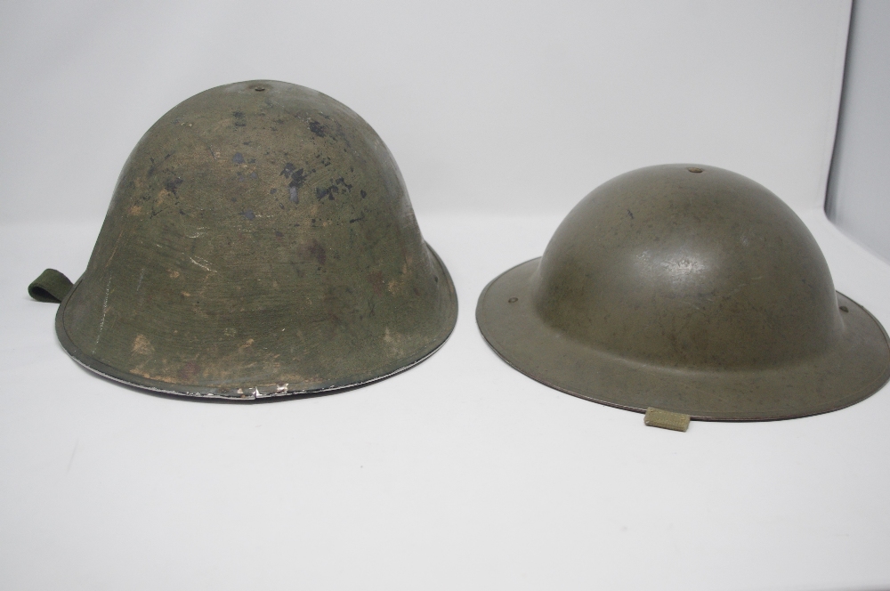 Two British military tin helmets dated 1952 and 1977.