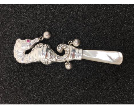 A silver baby's teething rattle in the form of a seahorse, set with ruby eyes.