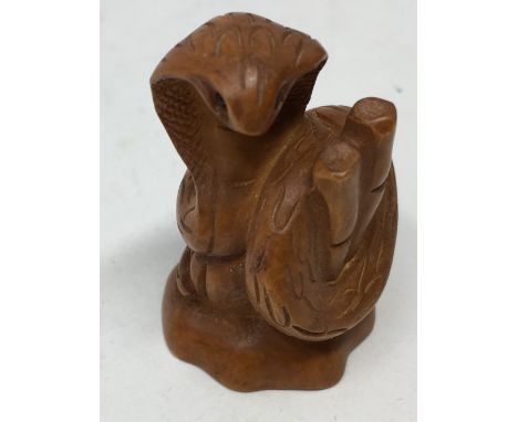 A Japanese fruitwood netsuke in the form of a cobra, with maker's signature to the base.